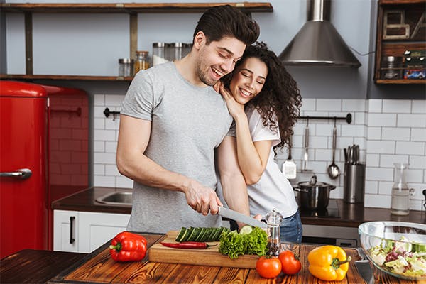 Picture-of-lovely-couple-man-and-woman-30s-cooking-salat-with-vegetables-together-in-modern-kitchen-at-home